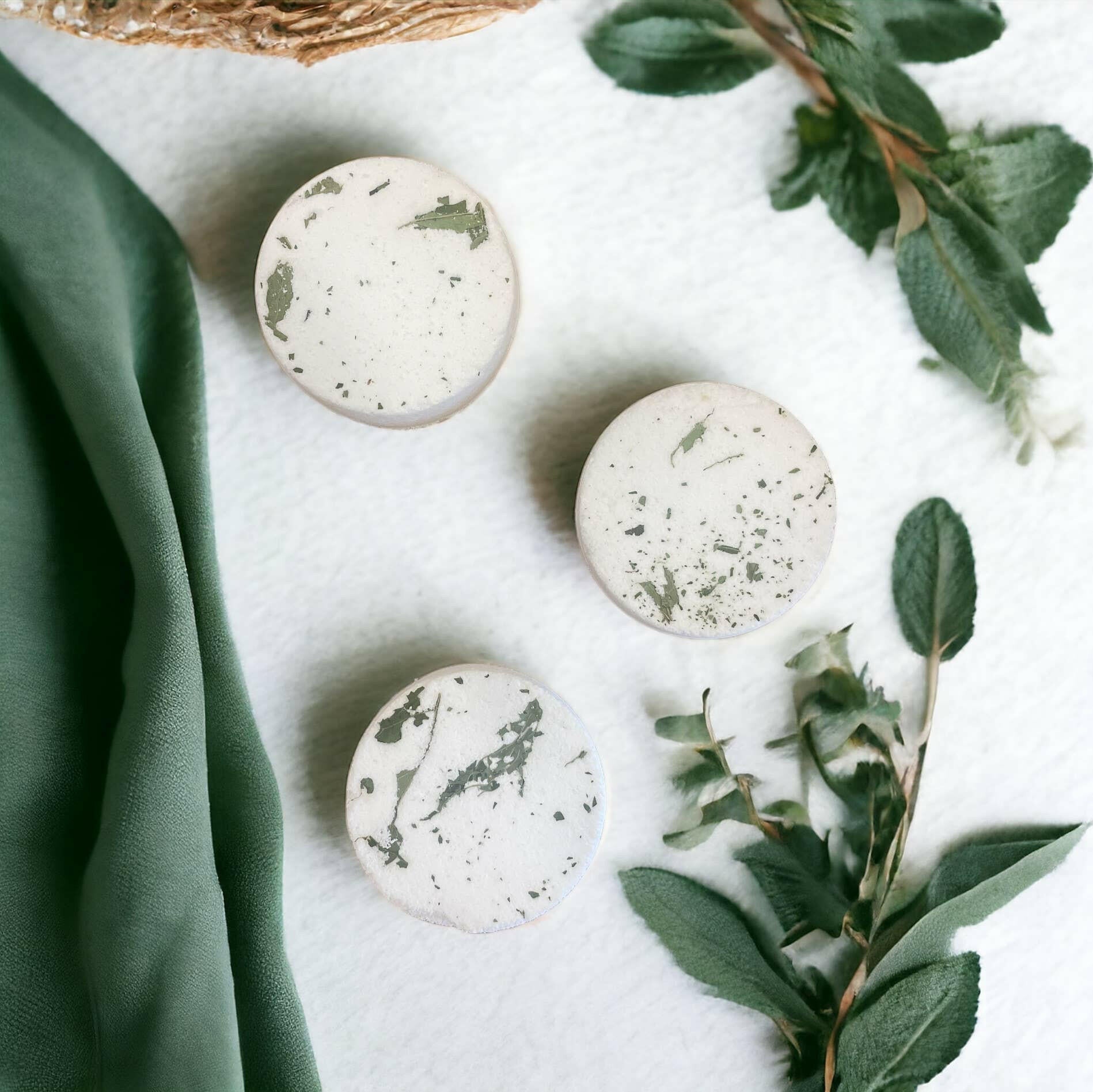 Mint Eucalyptus shower steamer on a white surface with green leaves and fabric.
